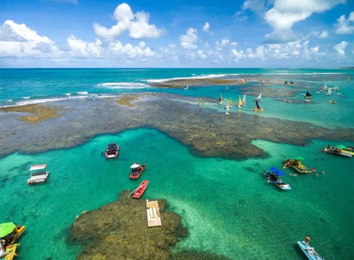 Vista aérea das piscinas naturais de Porto de Galinhas com jangadas e mar verde cristalino