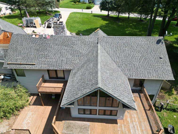 An aerial view of a house with a gray roof and a wooden deck.