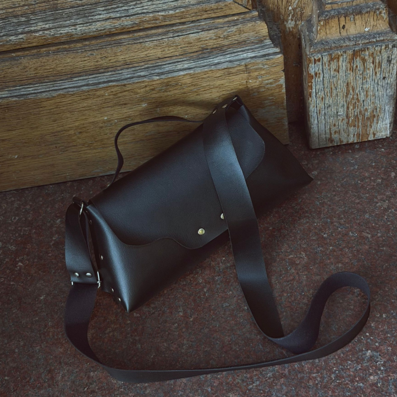 Mujer que sostiene un bolso tote de pana verde oscuro, de pie sobre unos escalones blancos.