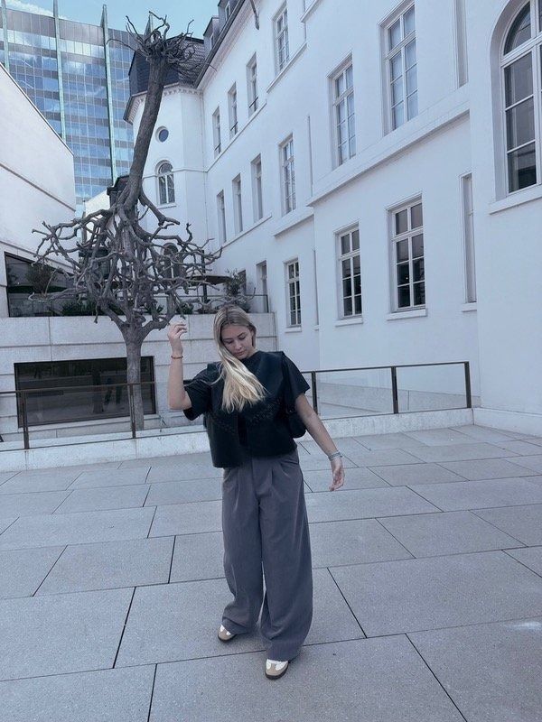 Una mujer vestida con pantalones grises y camisa negra