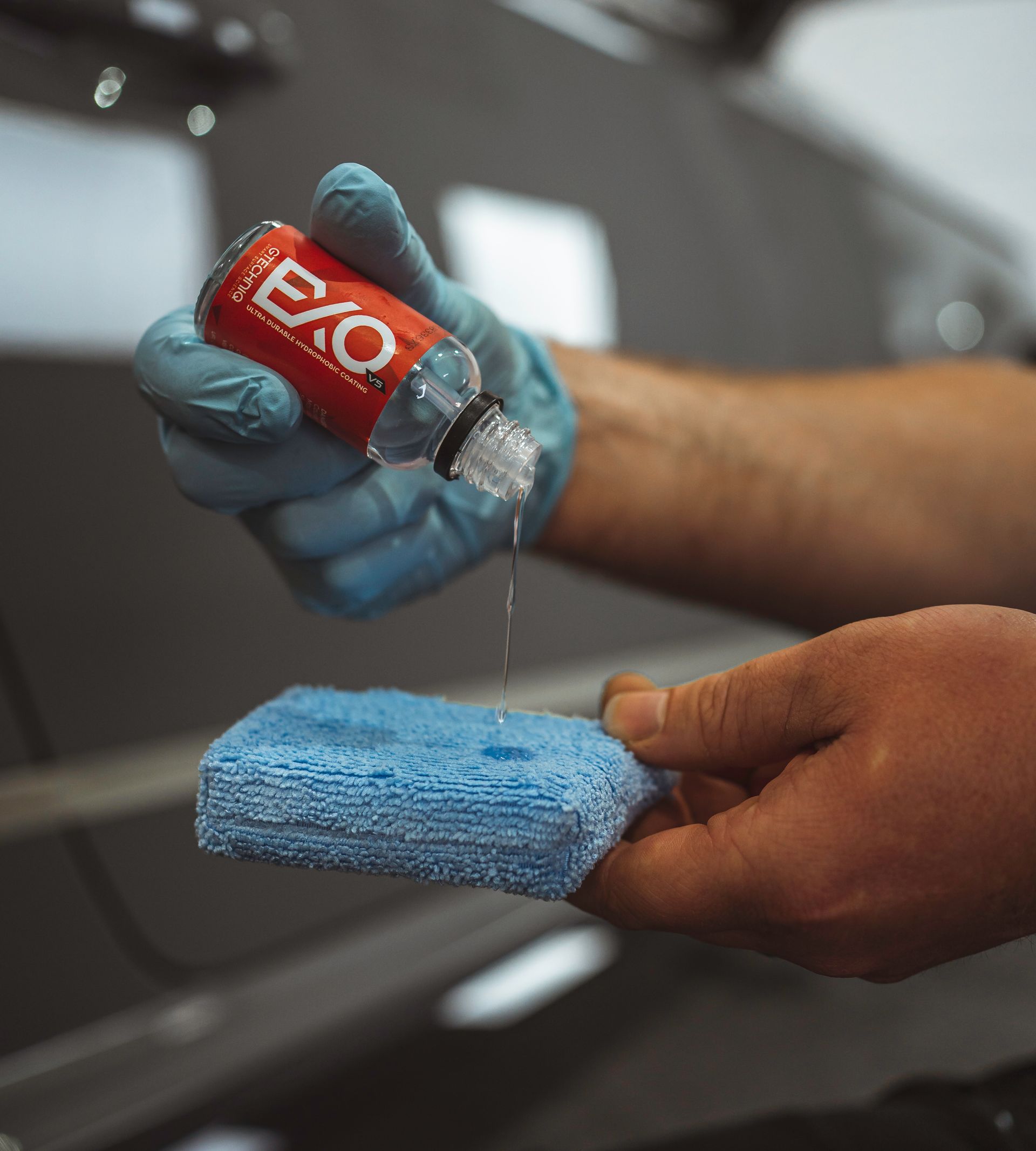 A person is holding a bottle of exo on a blue sponge