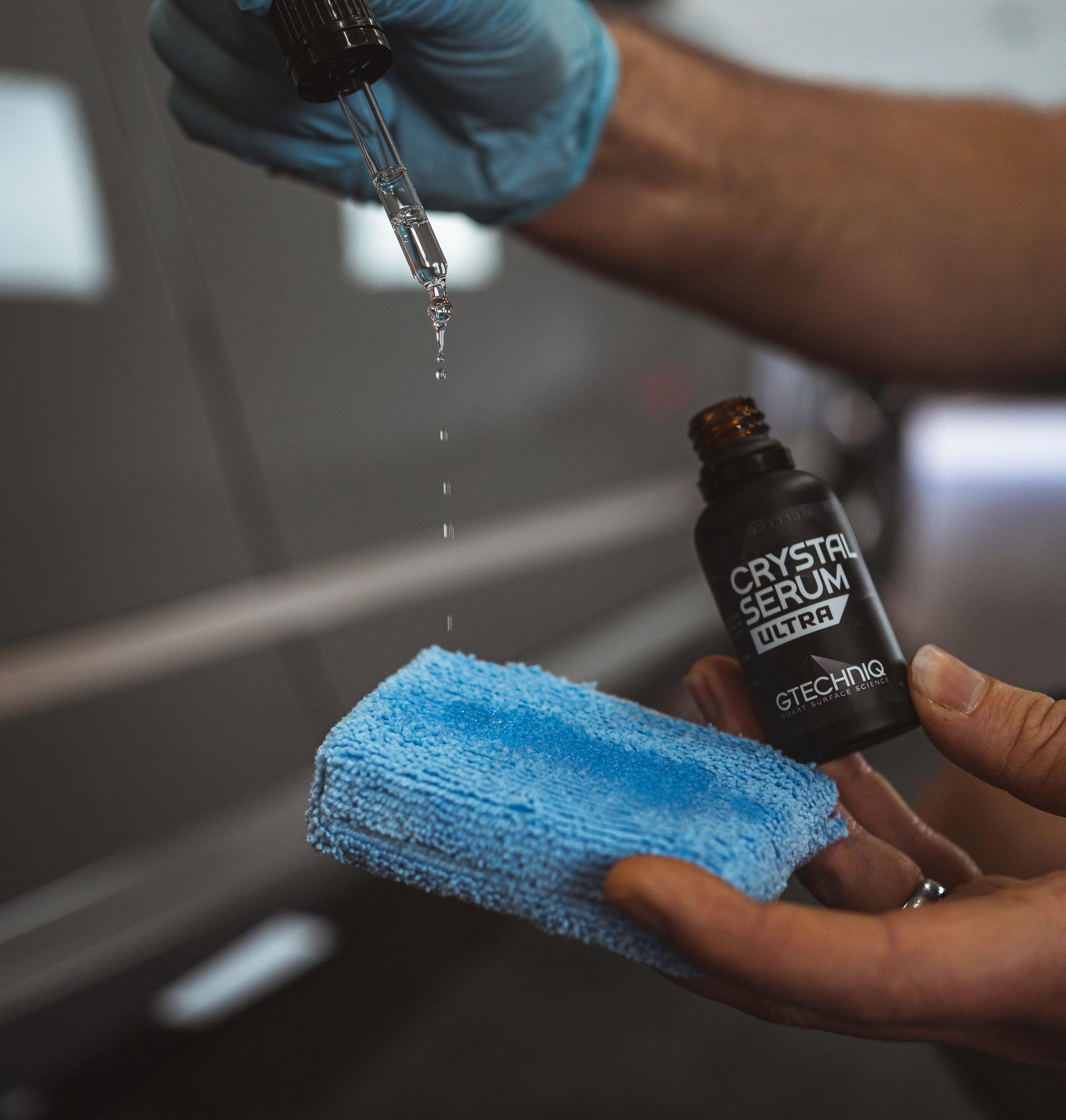 A person is holding a blue sponge and a bottle of crystal serum ultra.