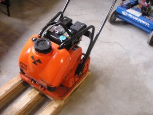 An orange machine is sitting on a wooden pallet.