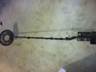 A metal detector is sitting on a concrete floor.