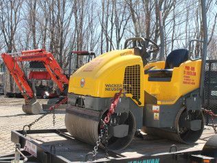 A yellow roller is sitting on top of a trailer.