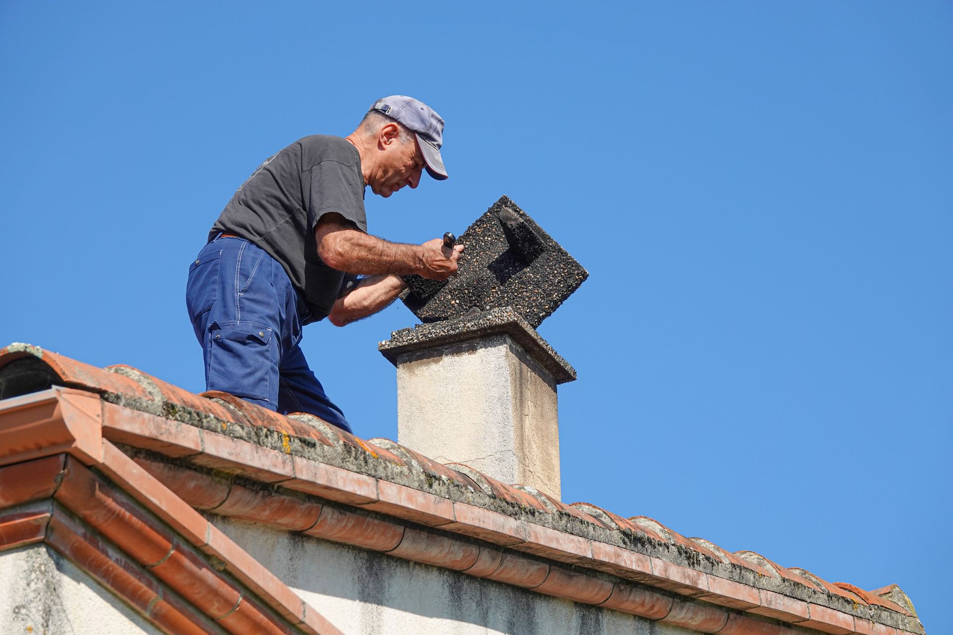 Worker repairs chimney on the roof. Worker repairs chimney on the roof.