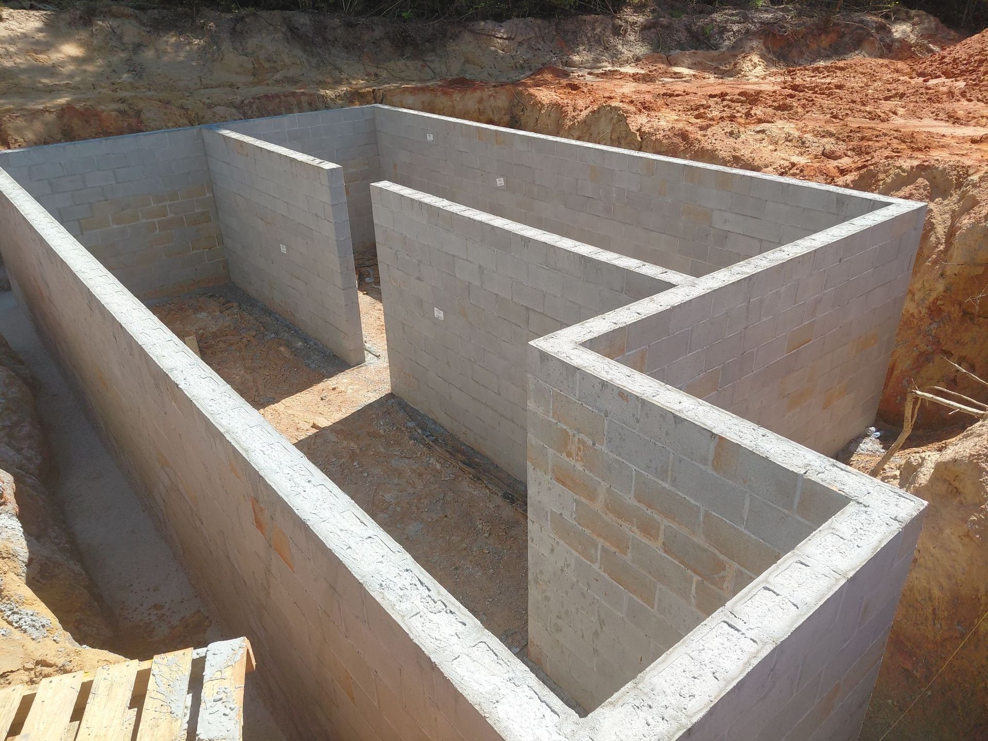 Foundation of a building constructed with gray cinder blocks, sitting in an excavated area.