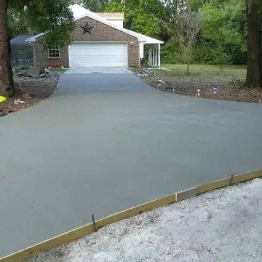 Concrete walkway through a yard, bordered by grass, a bush on the left, and a bright background.