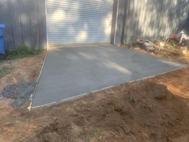 Newly poured concrete slab in front of a building with a roll-up door.
