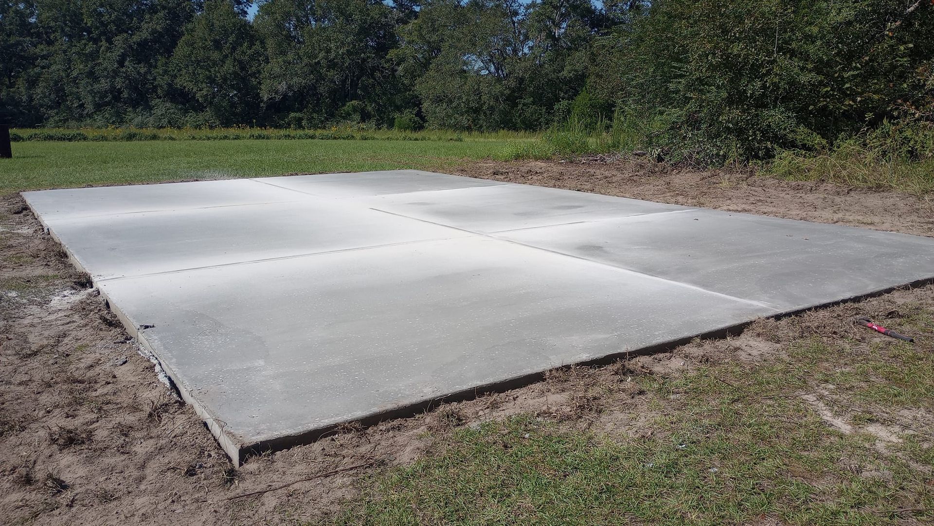 Gray concrete slabs, placed on dirt and grass, surrounded by trees.