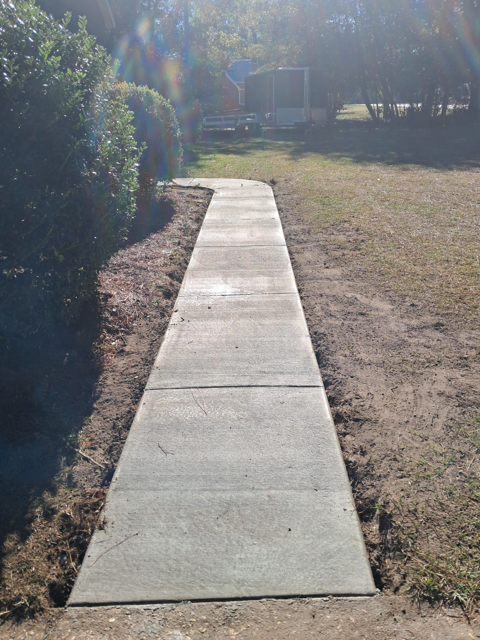 Concrete walkway through a yard, leading to a structure.