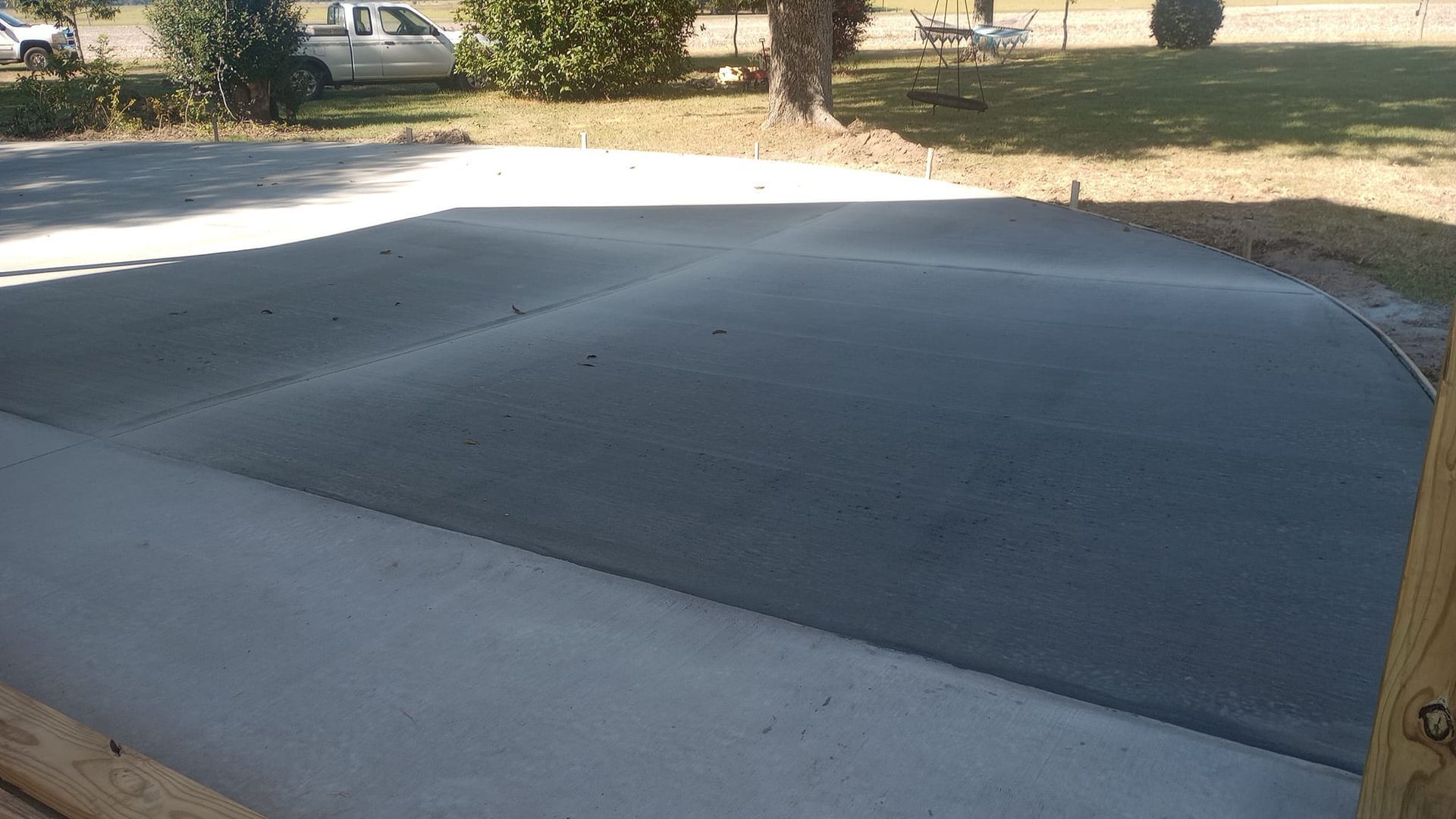 Newly poured concrete driveway with a rounded edge, outdoors in the daylight.