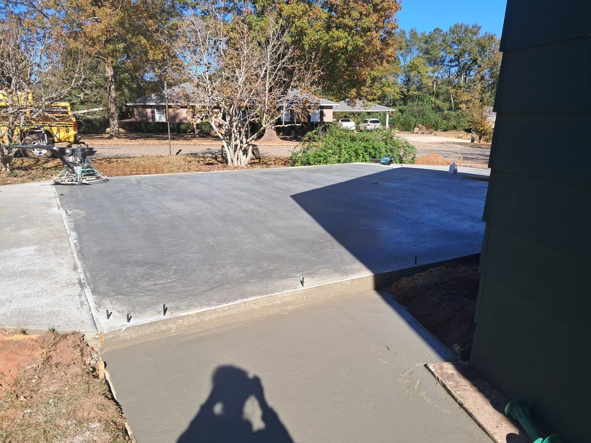 Newly poured concrete driveway and sidewalk next to a building on a sunny day.