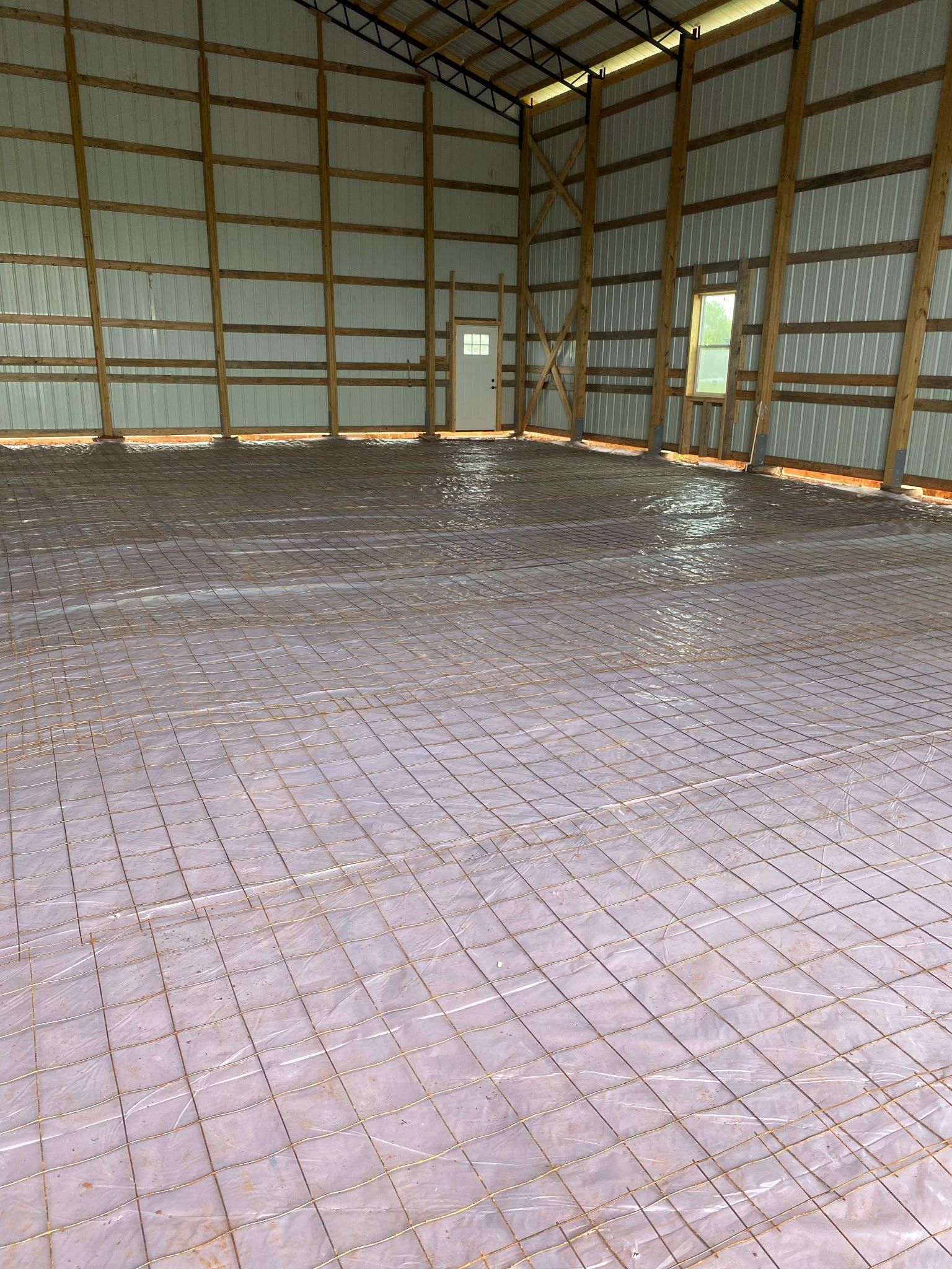 Interior of a large building with a concrete floor in the process of being poured. Rebar grid visible.