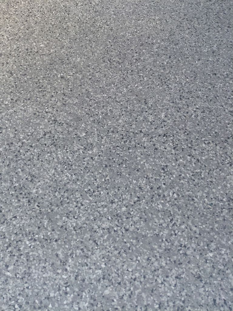 Close-up of a gray speckled flooring, showing various shades of gray and tiny dark flecks.