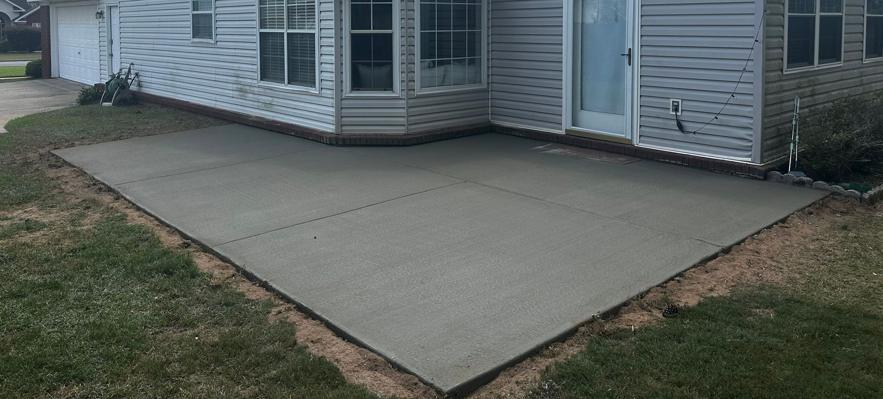 Golden retriever in a grassy yard near a patio with a dark wood pergola.