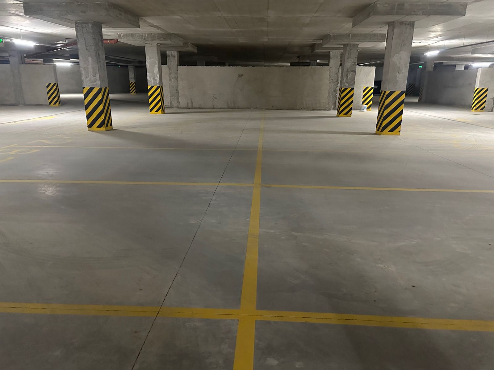 A newly poured concrete driveway with a person in a yellow shirt standing nearby, residential setting.