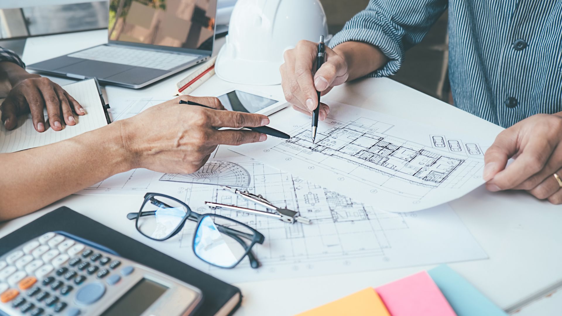 A group of people are sitting at a table looking at a blueprint.