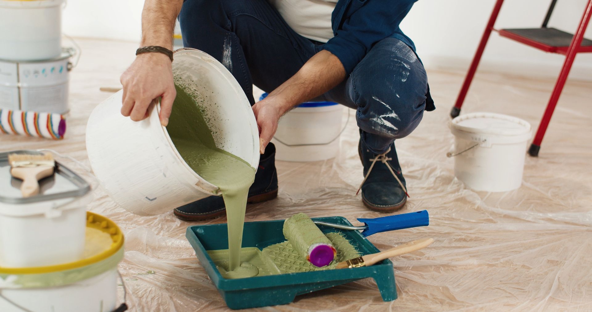 A man is pouring paint into a paint tray.