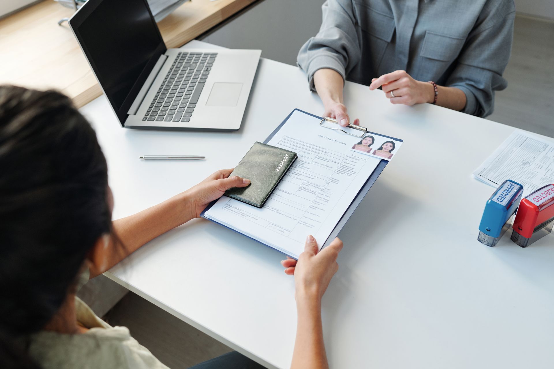 Business meeting with two people reviewing documents at a desk beside a laptop and stationery
