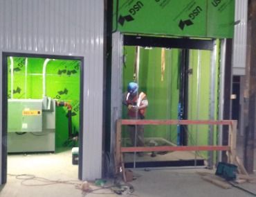 A Man is Welding in a Room With Green Walls