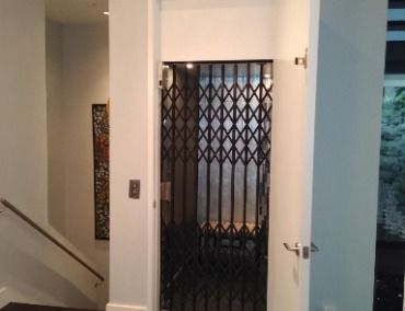 An Elevator With a Black Gate and Stairs in the Background