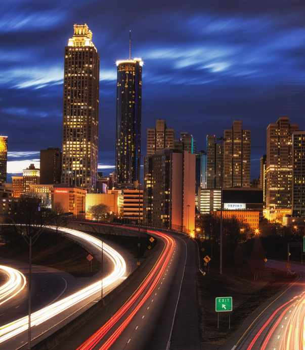 A highway going through a city at night with a green sign in the foreground