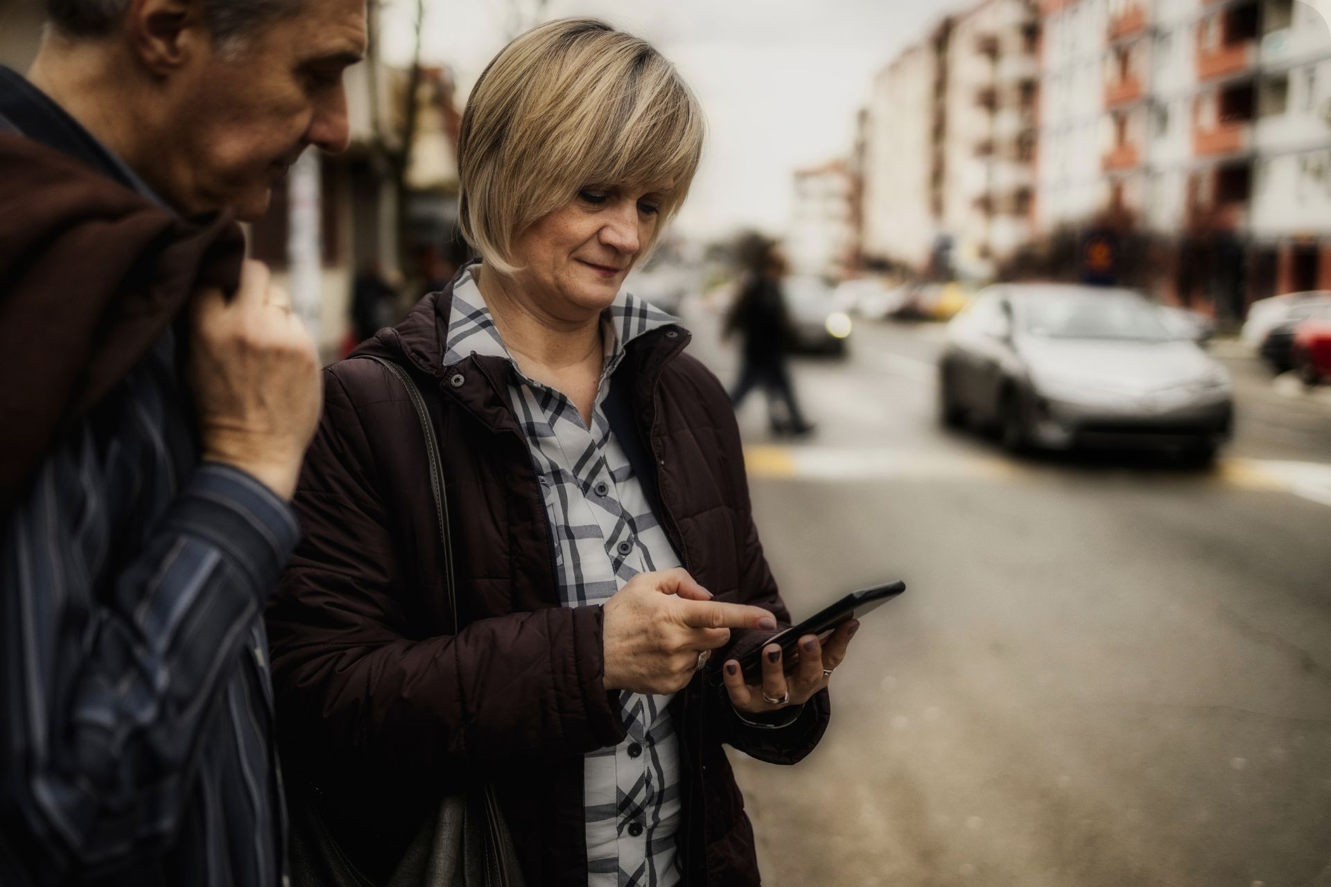 A man and a woman are standing on a street looking waiting on ride share company. EVENTS.LIMO