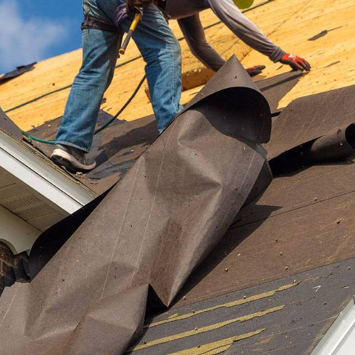 Roofers installing underlayment on a roof, preparing for shingles.