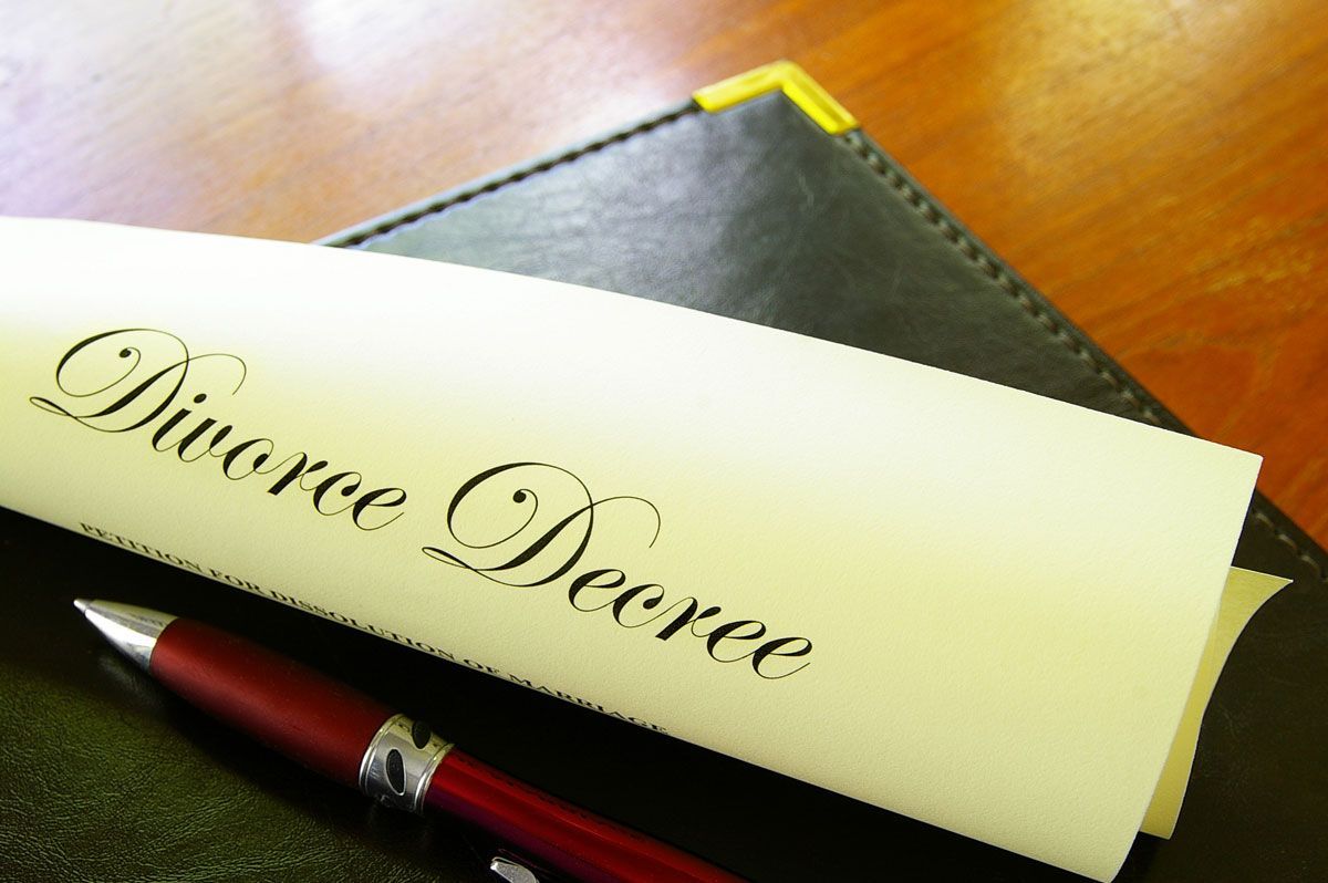 Divorce decree document with a pen on a black leather notepad on a wooden table.