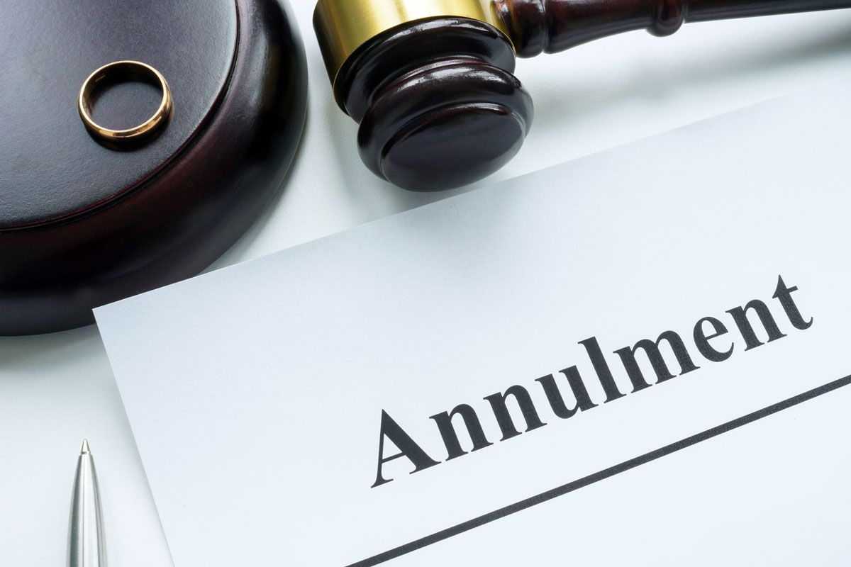 Annulment document with gavel, wedding ring, and pen on a white surface.