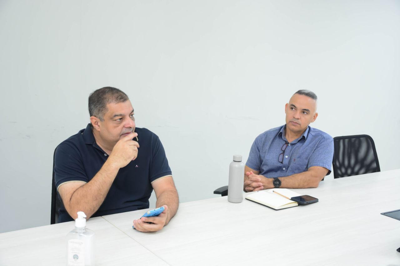 Dois homens estão sentados à mesa conversando entre si.