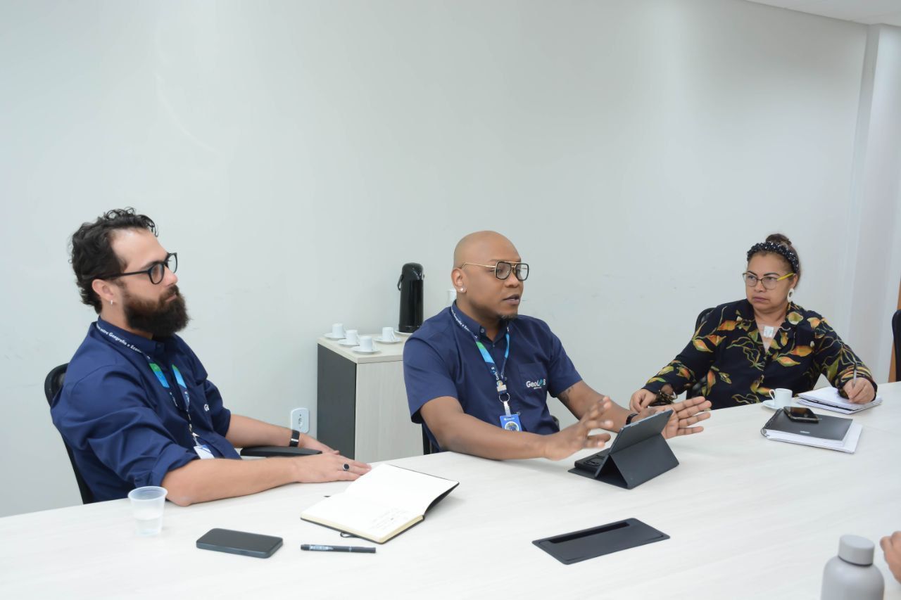 Um grupo de pessoas está sentado à mesa com um tablet.