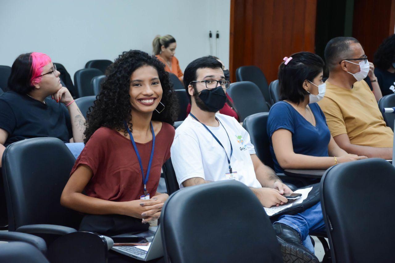 Um grupo de pessoas usando máscaras faciais estão sentadas em uma sala de aula.