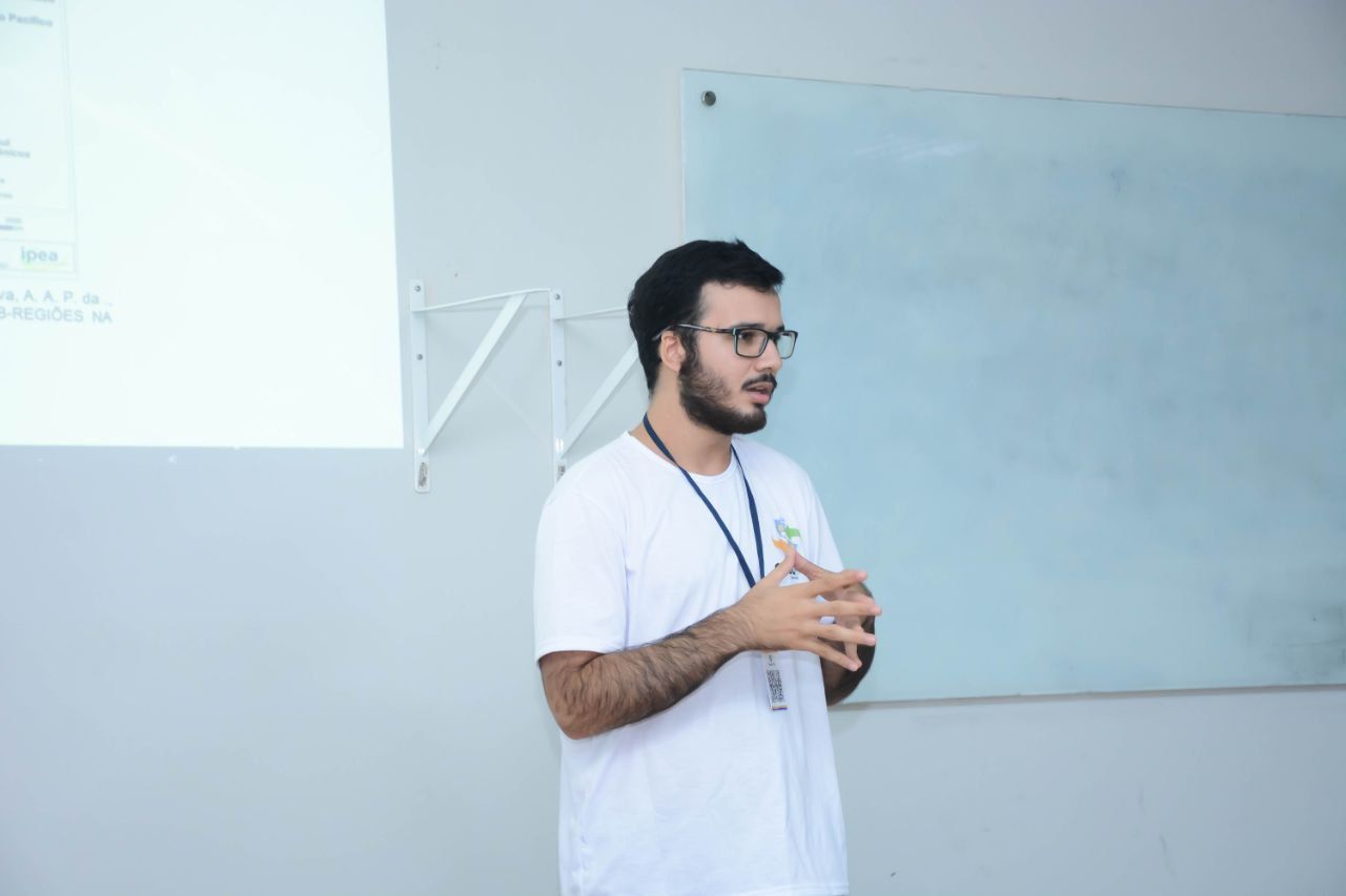 Um homem está fazendo uma apresentação em frente a um quadro branco em uma sala de aula.