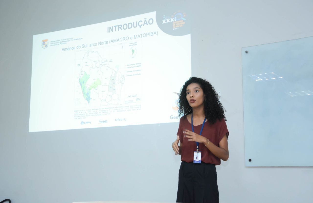 Uma mulher está fazendo uma apresentação em frente a uma tela de projetor.