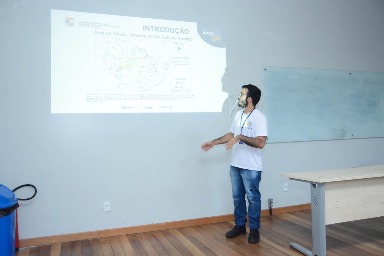 Um homem está fazendo uma apresentação em frente a uma tela de projetor.