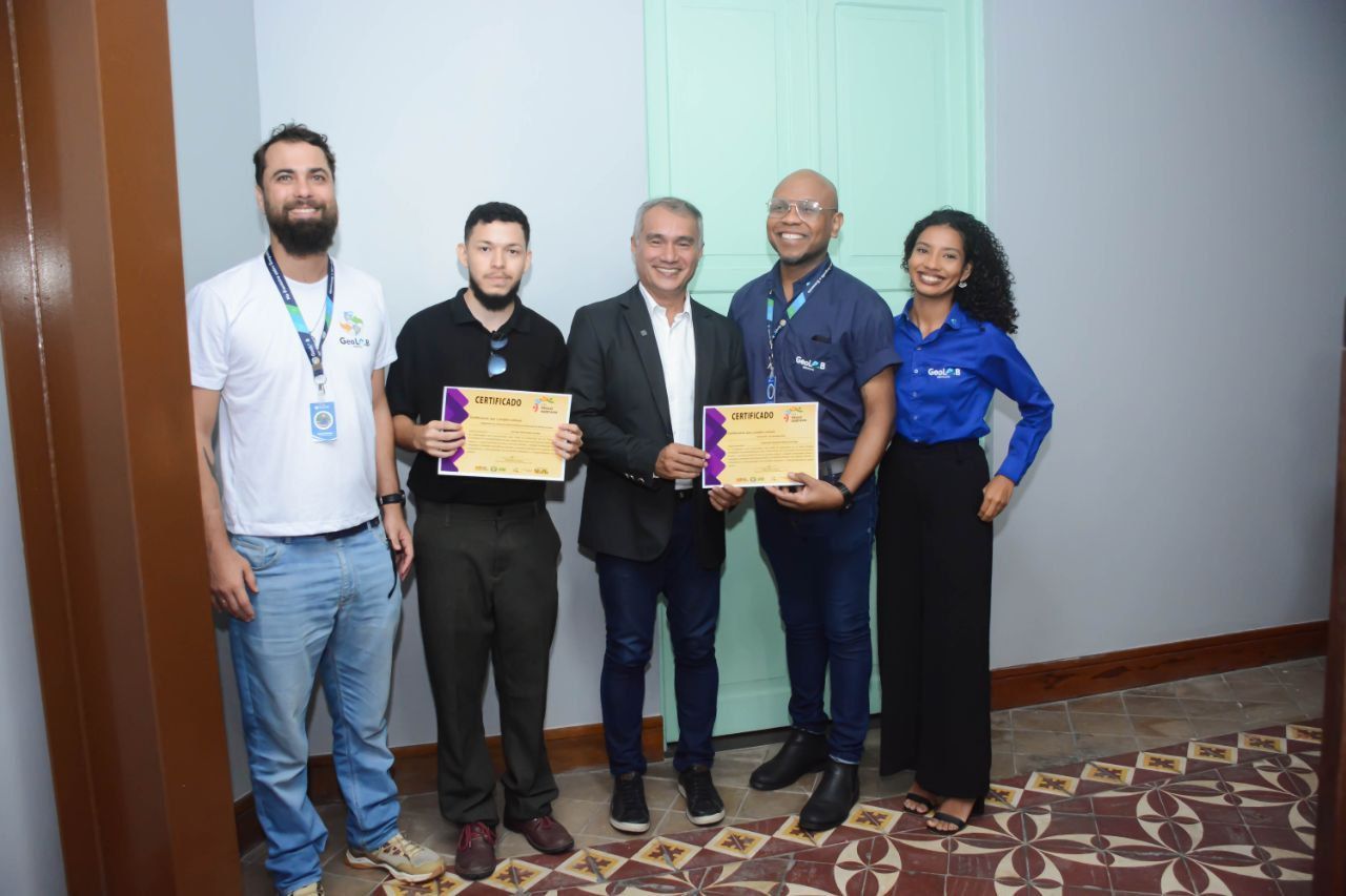 Um grupo de pessoas estão de pé, uma ao lado da outra, segurando certificados.