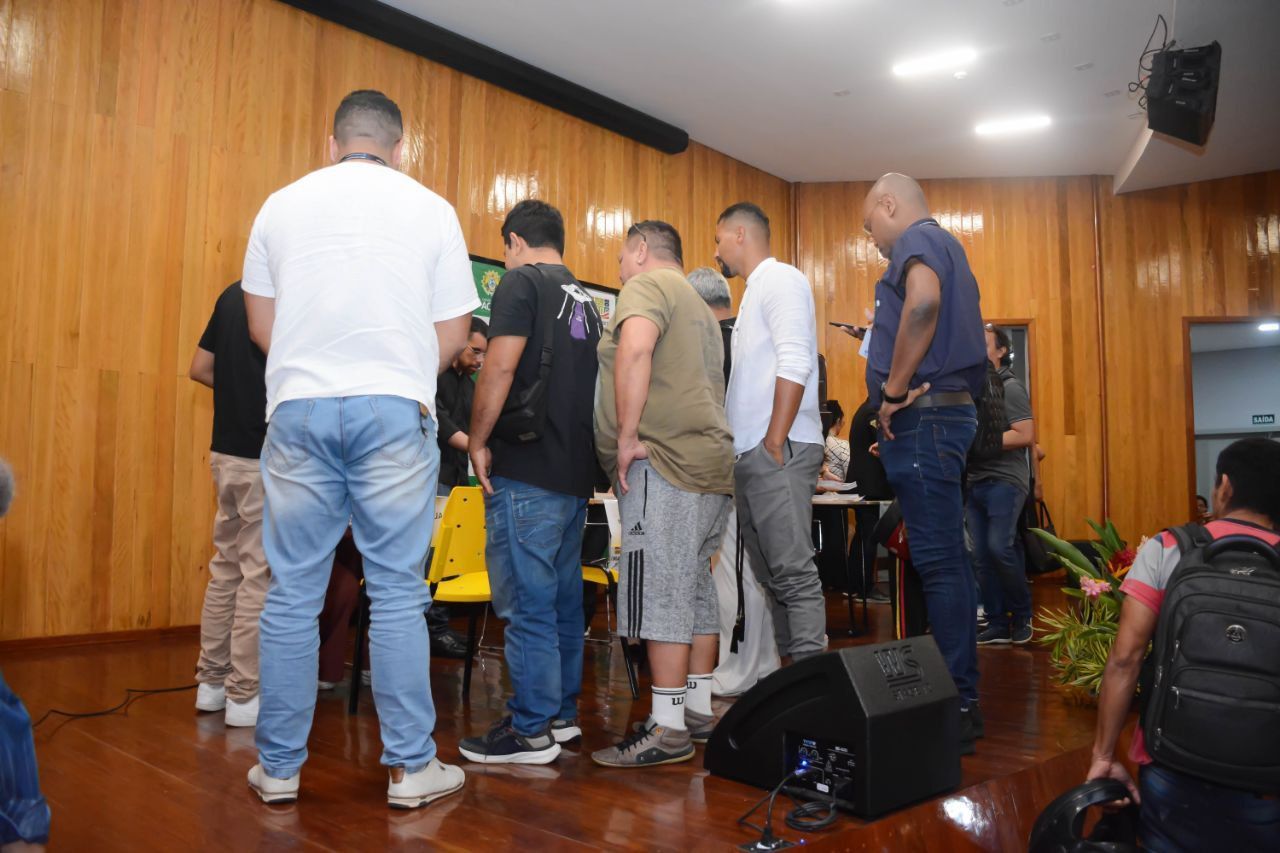 Um grupo de homens está em pé em uma sala em frente a um microfone.
