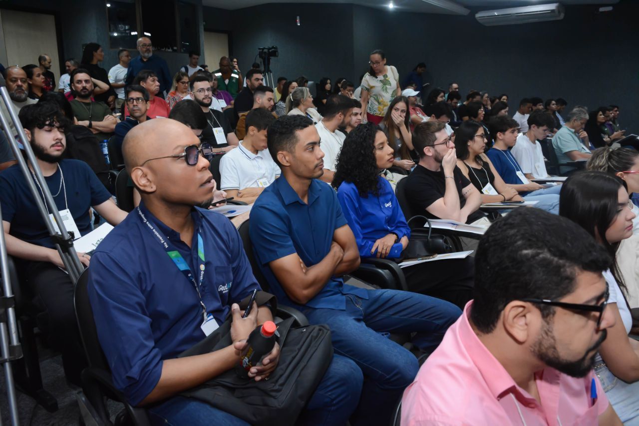 Um grupo de pessoas está sentado em uma sala assistindo a uma apresentação