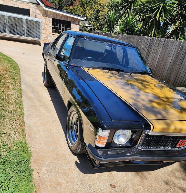 A Black Car With a Yellow Hood is Parked in a Driveway — Roadworthy's On The Run in Harristown, QLD