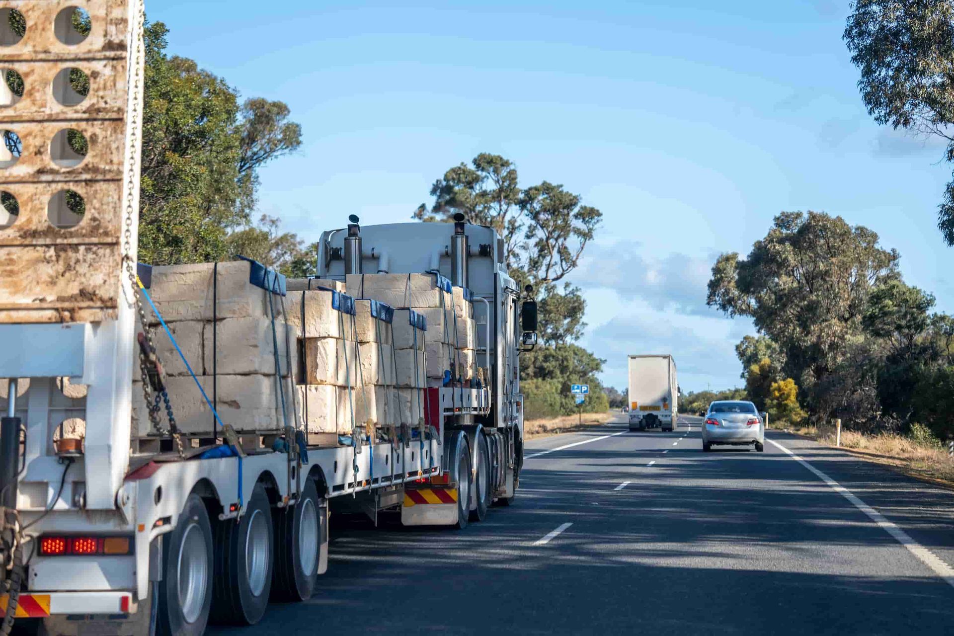 A Semi Truck is Driving Down a Highway Next to a Car — Roadworthy's On The Run in Harristown, QLD