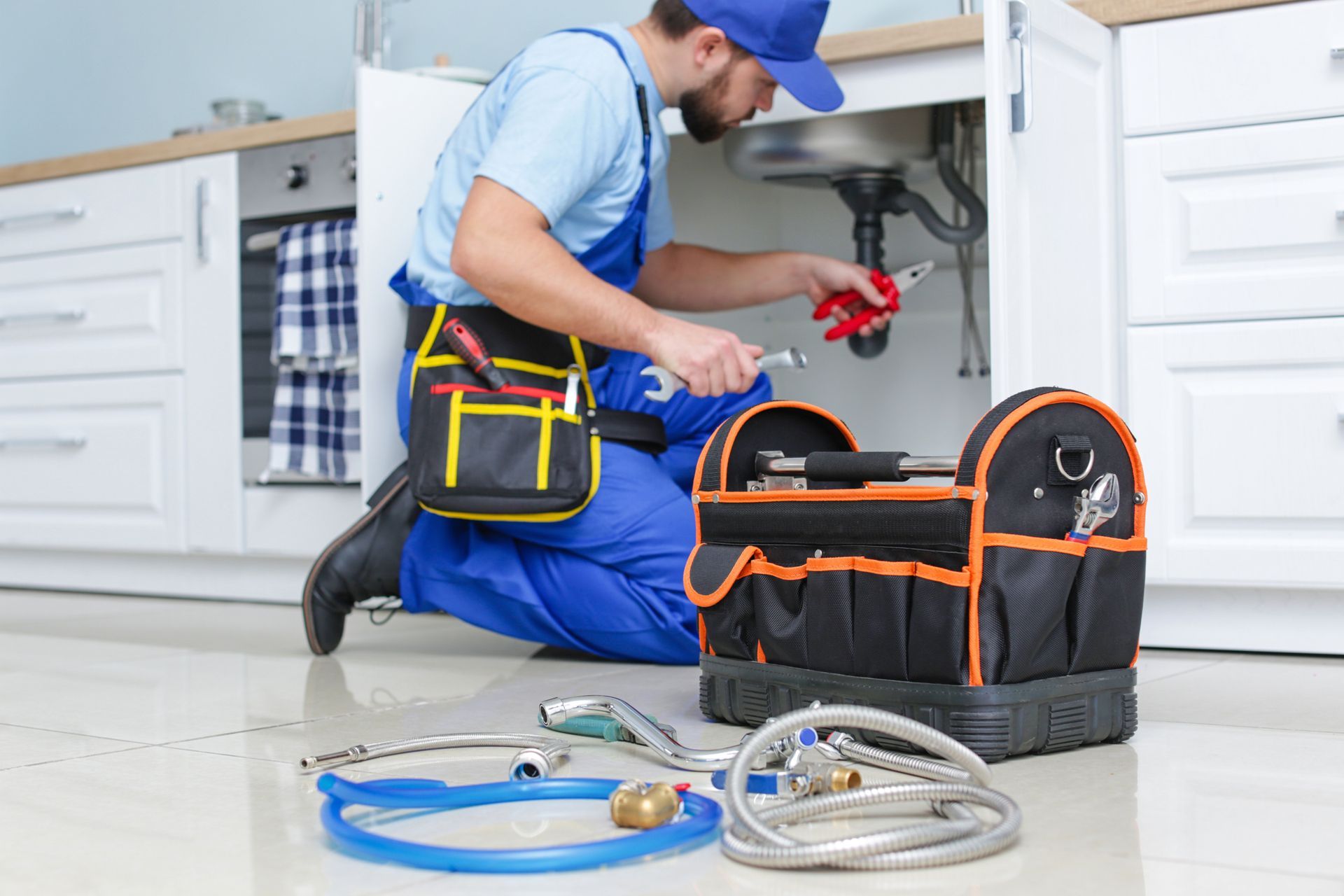 A plumber is fixing a sink in a kitchen.
