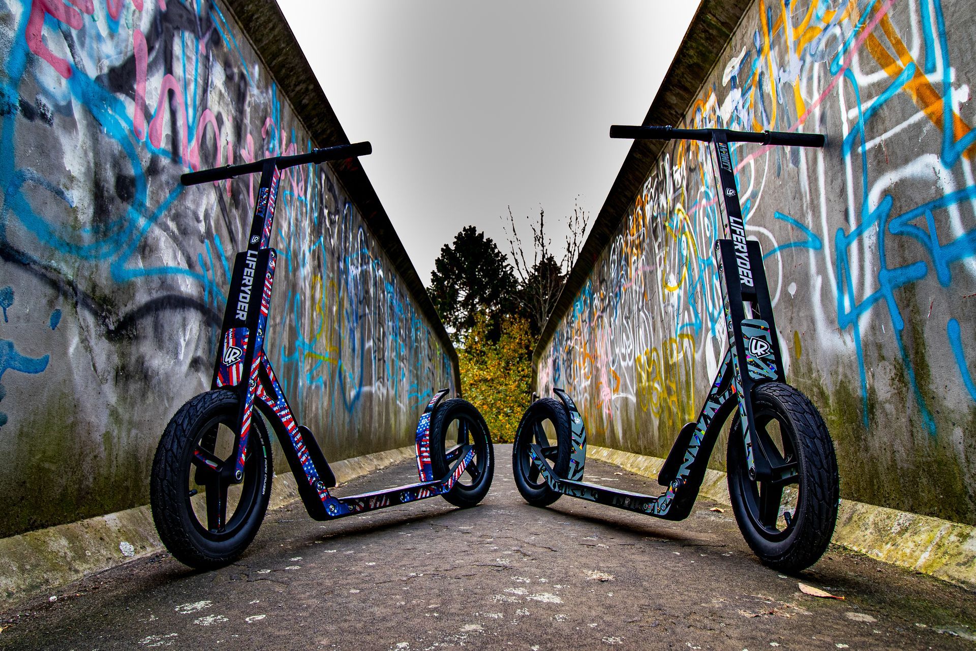 Two black scooters with graffiti background.