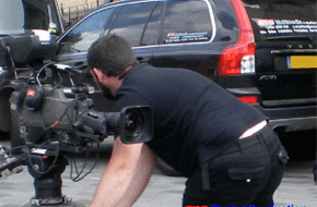 Camereman with professional camera filming a car