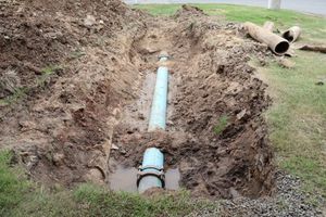 A blue pipe is sitting in the middle of a muddy hole.