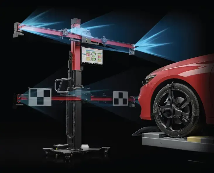Wheel alignment machine measuring a red car's front wheels. Blue beams project from the machine.