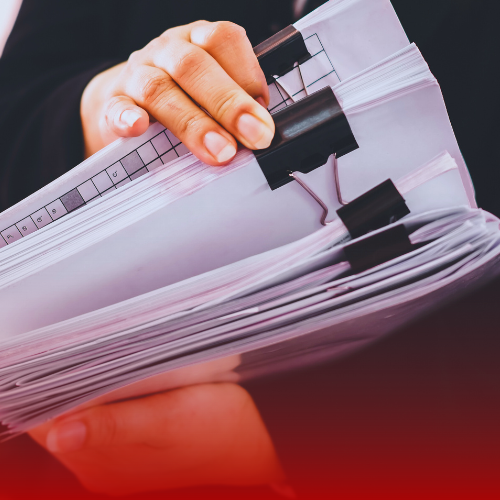 A person is holding a stack of papers with binder clips