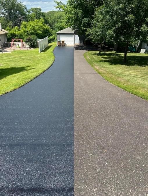 A person applies a layer of sealcoating to an asphalt driveway, ensuring its protection and longevity.