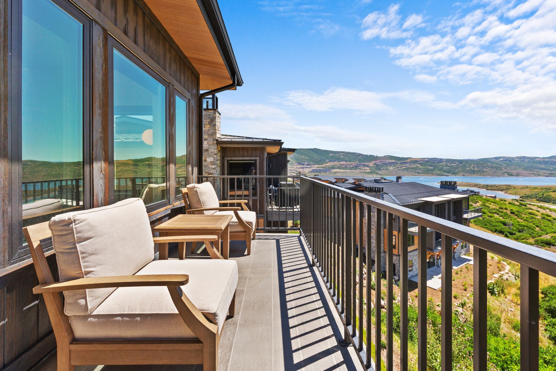 Balcony with seating overlooking a scenic landscape, a lake in the distance.